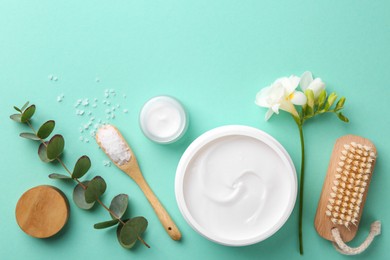 Photo of Jars of cream, body care products and eucalyptus branch on turquoise background, flat lay. Space for text