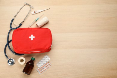 Photo of First aid kit on light wooden table, flat lay. Space for text