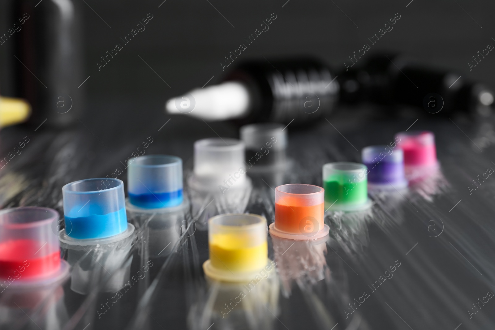 Photo of Many caps with colorful tattoo inks on table