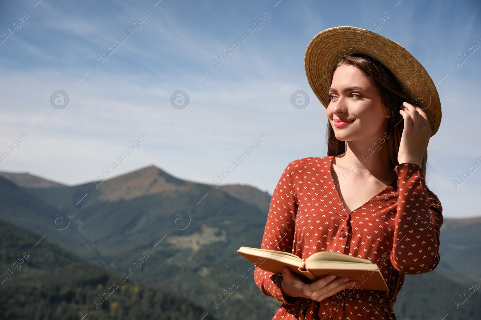 Photo of Beautiful young woman reading book in mountains, space for text