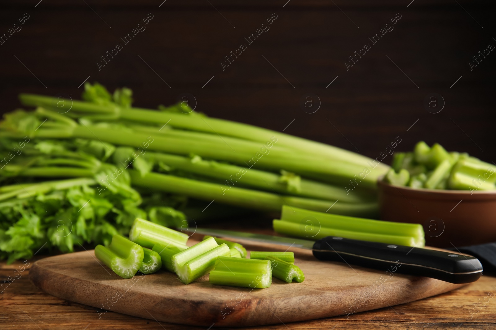 Photo of Cut fresh green celery on wooden board