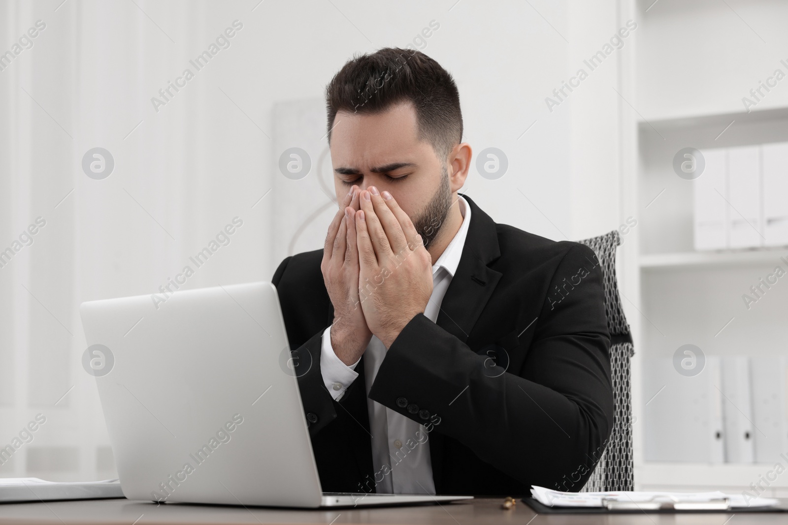 Photo of Sick man coughing at workplace in office