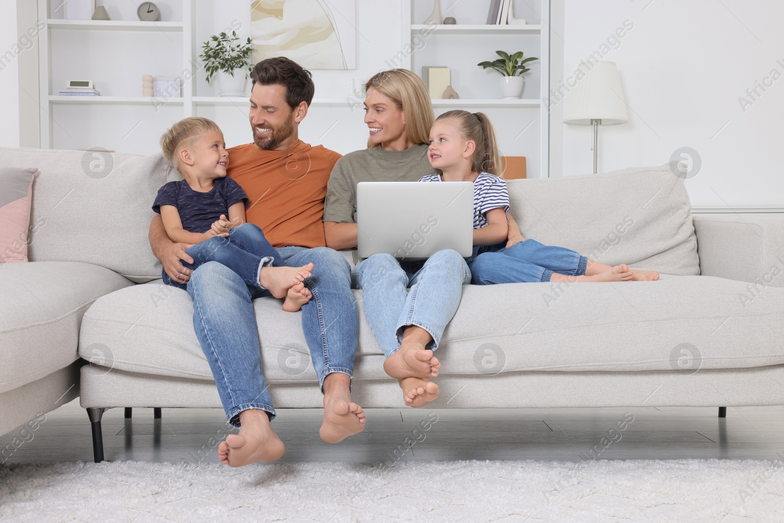 Photo of Happy family with laptop spending time together on sofa at home