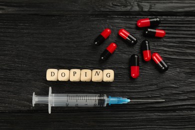 Cubes with word Doping and drugs on black wooden background, flat lay
