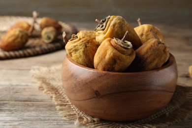 Bowl with tasty dried persimmon fruits on wooden table