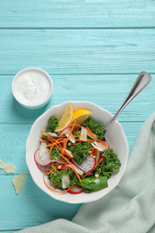 Tasty fresh kale salad on light blue wooden table, flat lay