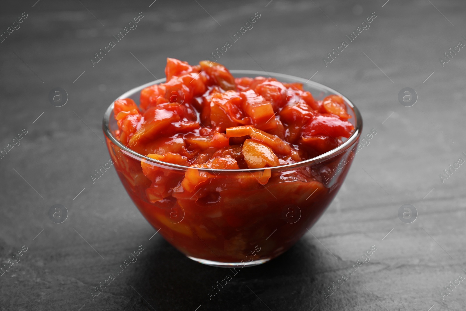 Photo of Delicious lecho in glass bowl on black table