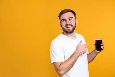 Handsome man with cold kvass on yellow background. Traditional Russian summer drink