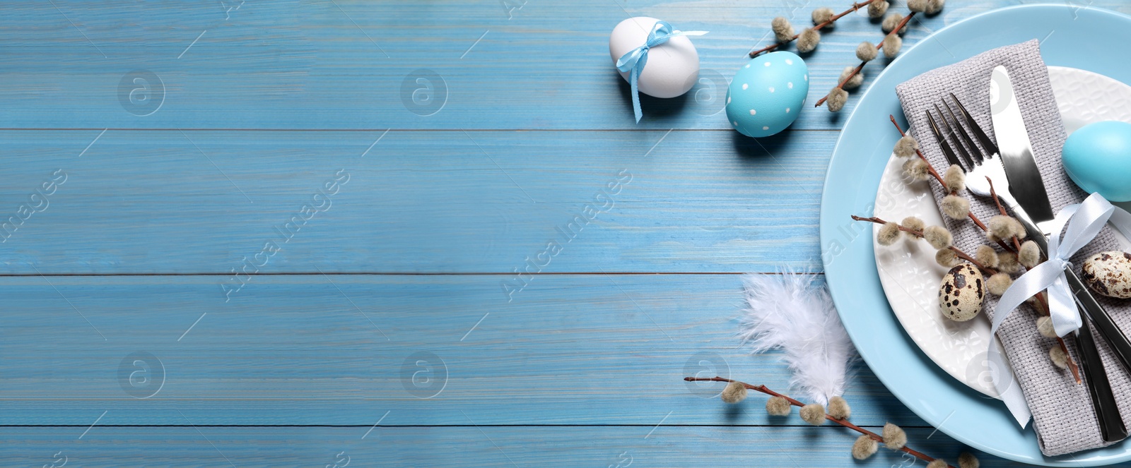 Image of Festive Easter table setting with eggs on light blue wooden background, flat lay. Space for text