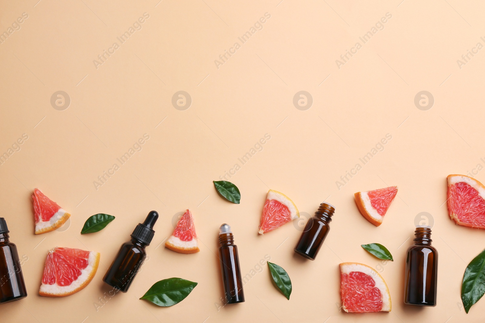 Photo of Flat lay composition with grapefruit slices and bottles of essential oil on color background, space for text