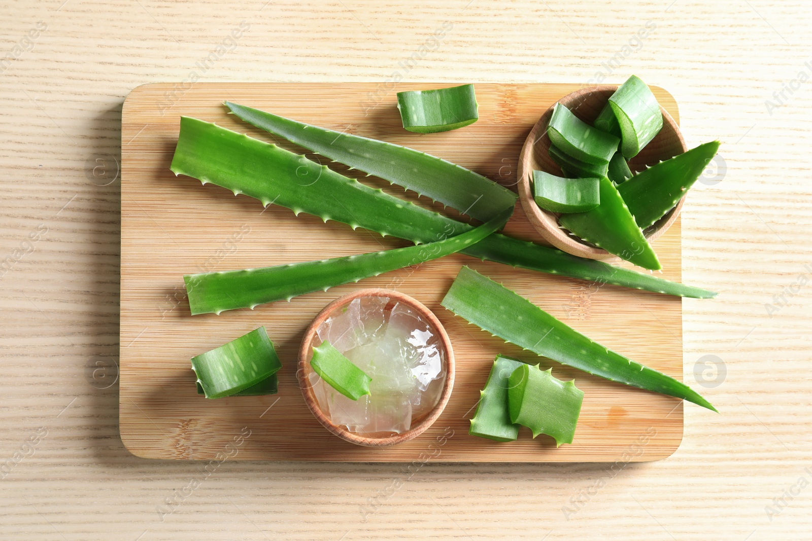 Photo of Flat lay composition with bowl of peeled aloe vera and green leaves on wooden table