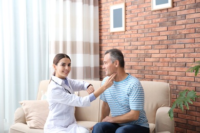 Photo of Doctor checking mature man's pulse with fingers at home