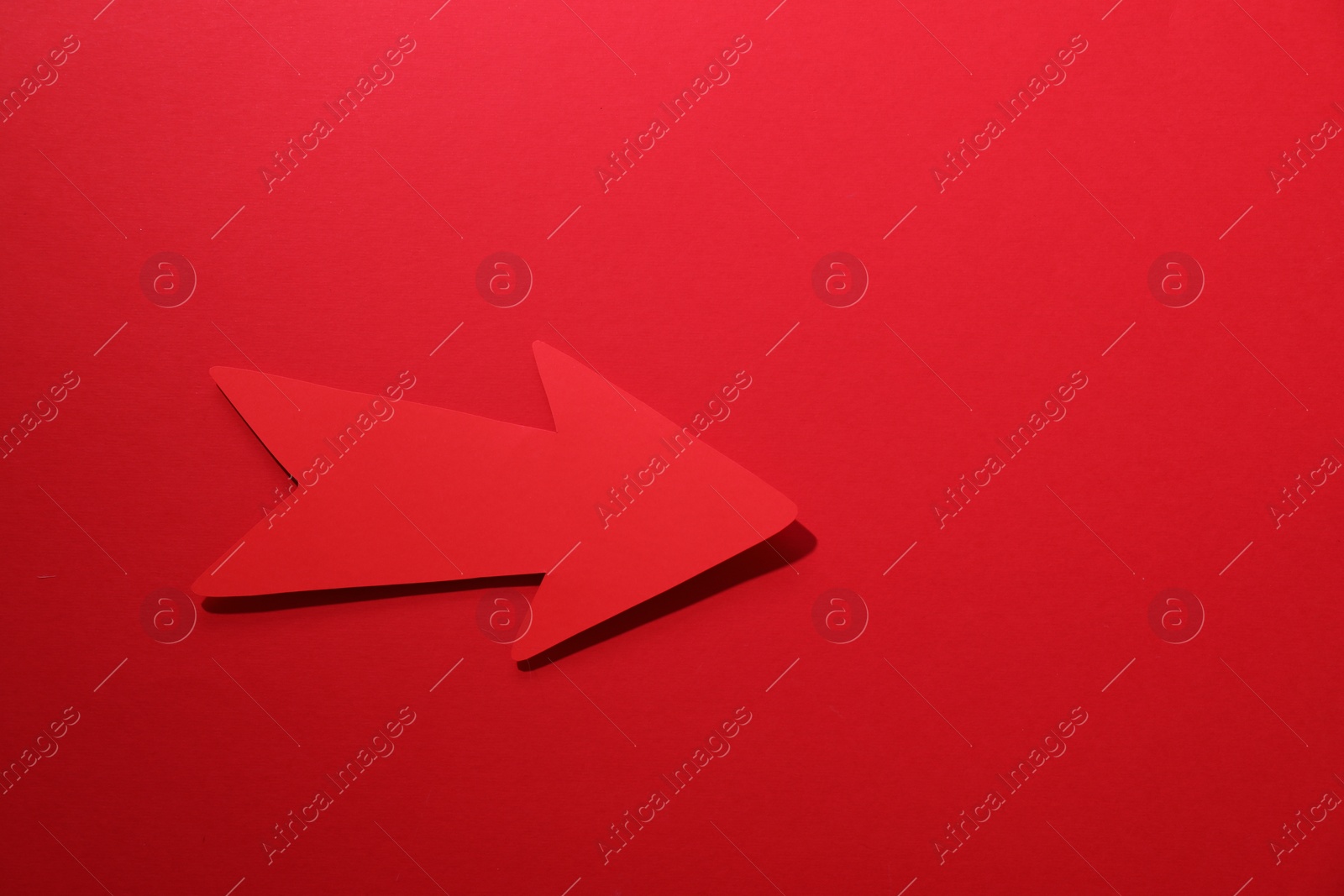 Photo of One paper arrow on red background, top view. Space for text