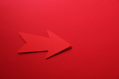 Photo of One paper arrow on red background, top view. Space for text