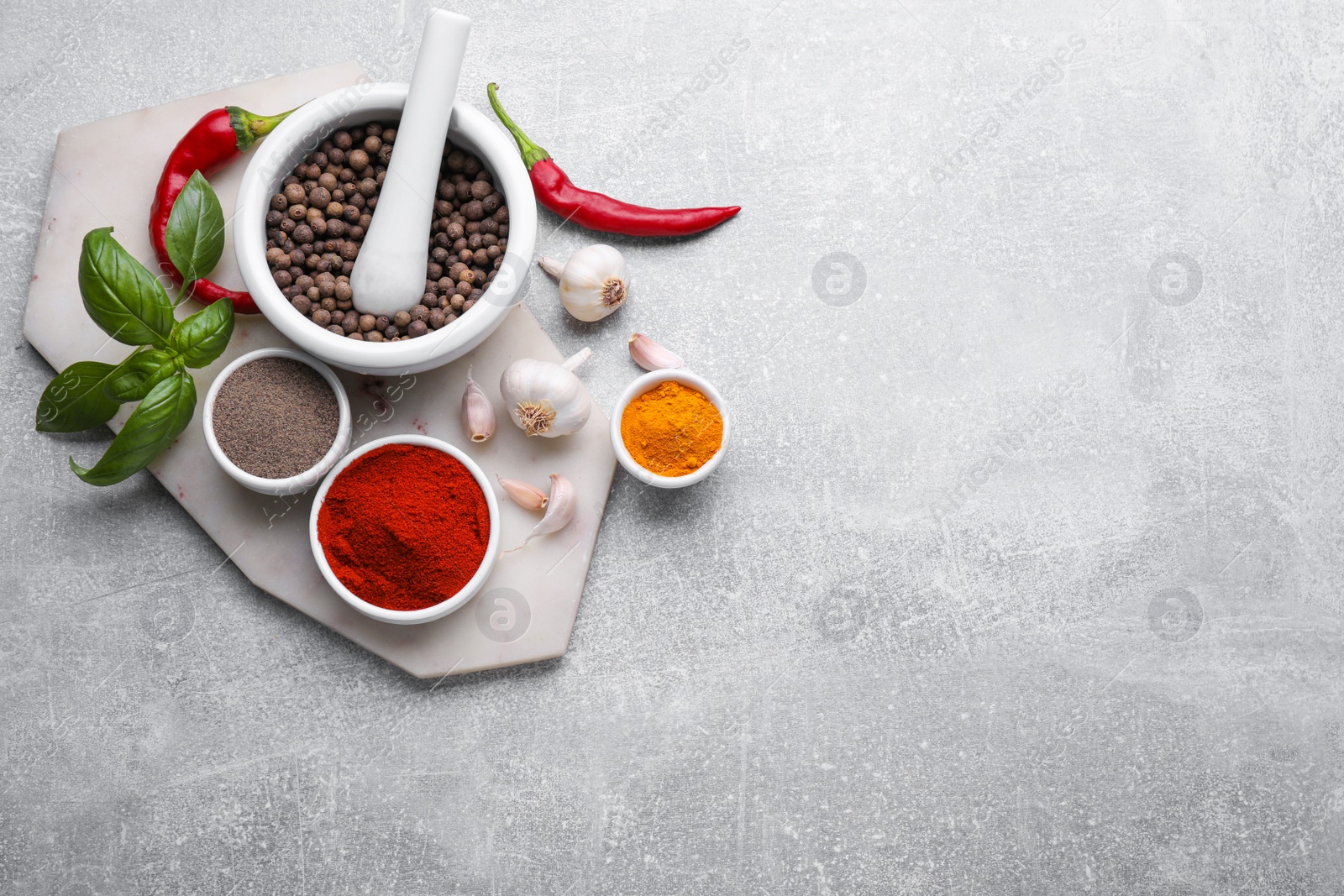 Photo of Mortar with pestle and different spices on light grey table, flat lay. Space for text