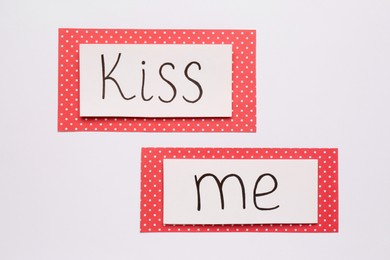 Photo of Cards with phrase Kiss me on white background, top view