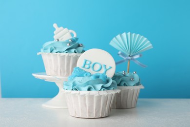Baby shower cupcakes with toppers on white table against light blue background