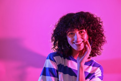 Photo of Beautiful young woman posing on color background in neon lights. Space for text