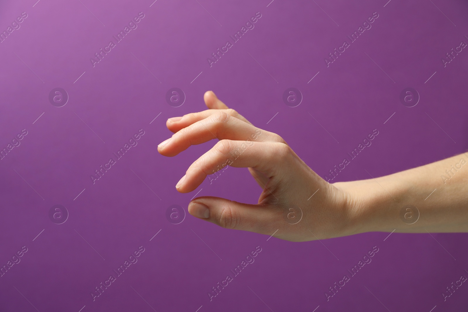 Photo of Woman holding something in hand on purple background, closeup. Space for text