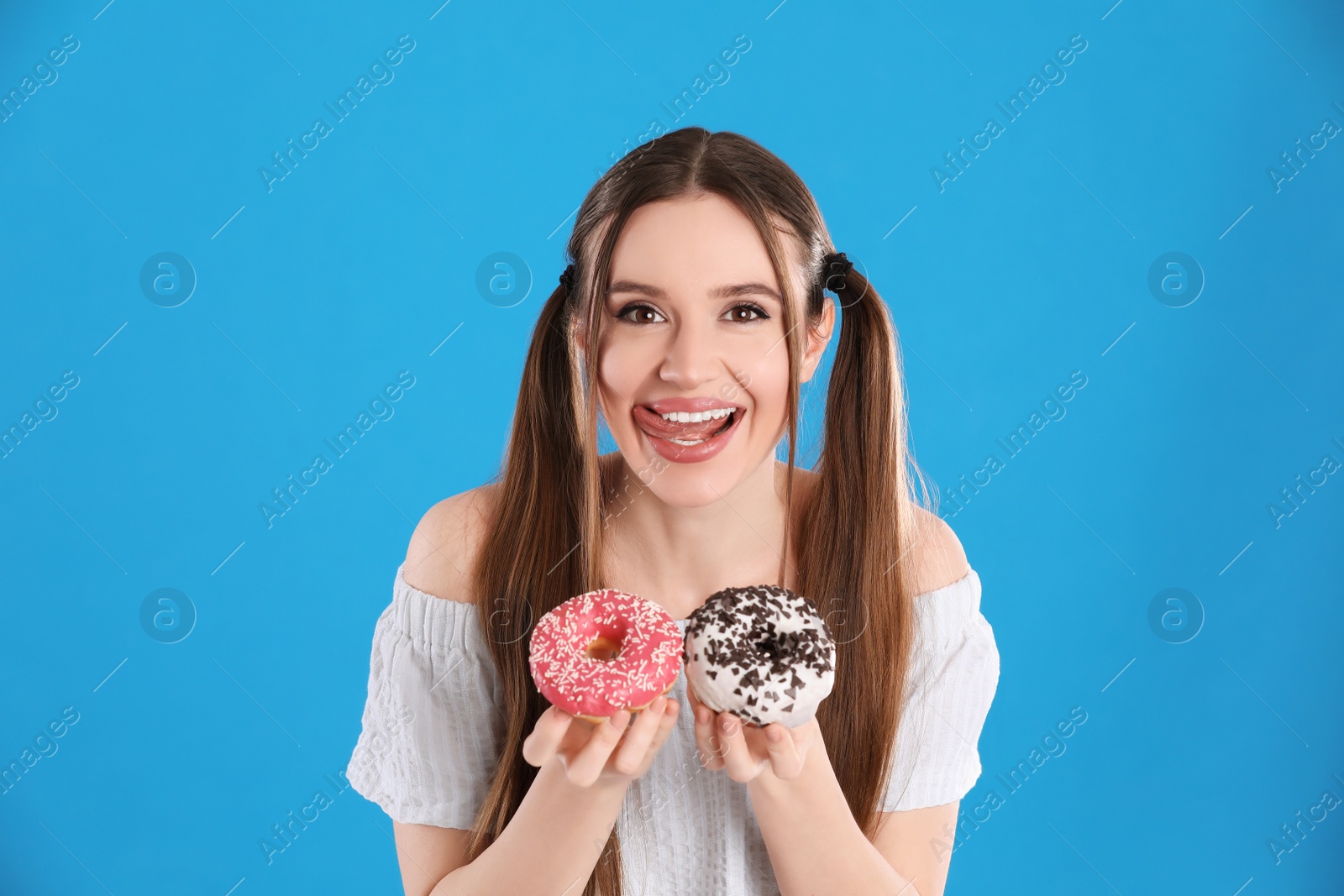 Photo of Beautiful young woman with donuts on light blue background