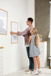 Father and daughter hanging picture on wall at home