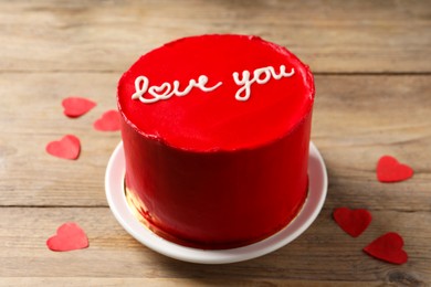 Photo of Bento cake with text Love You and paper hearts on wooden table. St. Valentine's day surprise