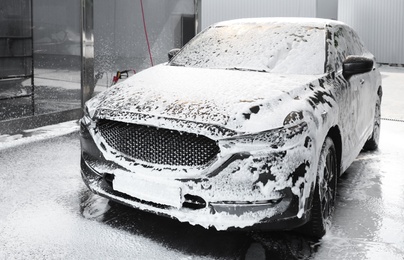 Photo of Luxury automobile covered with foam at car wash