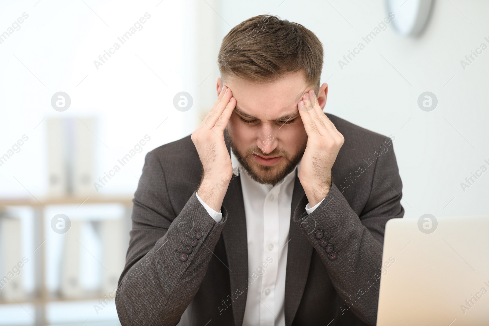 Photo of Young man suffering from migraine in office