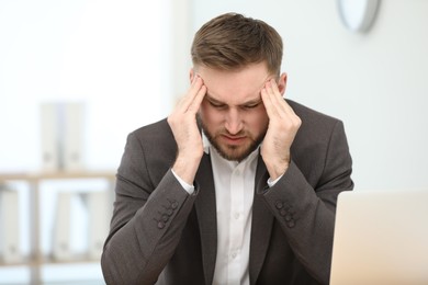 Photo of Young man suffering from migraine in office