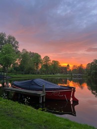 Photo of Scenic view of pond with moored boat at sunset