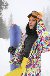 Photo of Young woman with snowboard wearing winter sport clothes outdoors