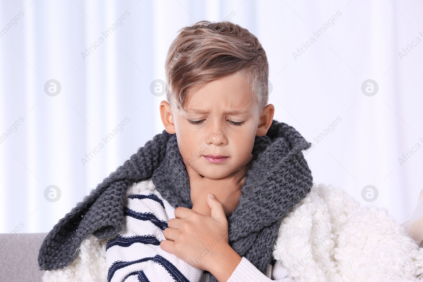 Photo of Ill boy suffering from cough on sofa at home