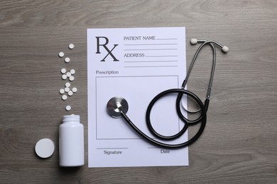 Photo of Medical prescription form, stethoscope and pills on wooden table, flat lay