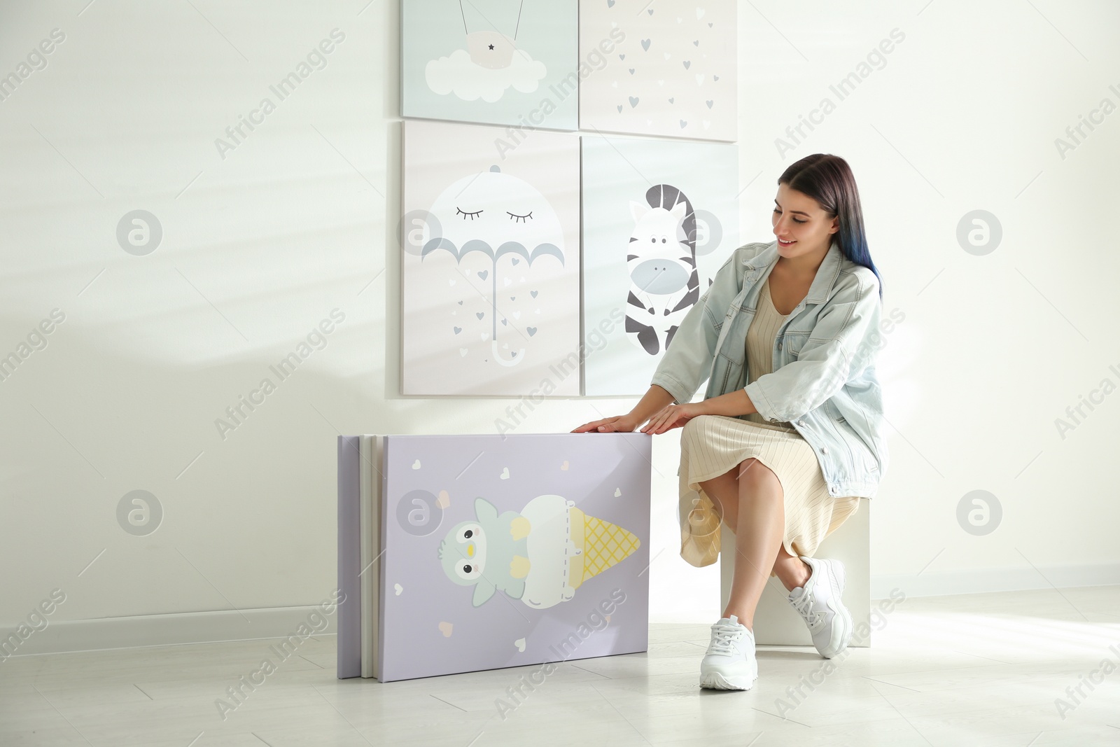 Photo of Decorator choosing picture near white wall. Children's room interior design