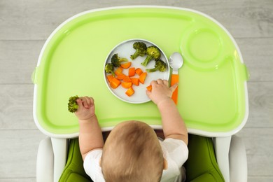 Photo of Cute little baby eating healthy food, top view