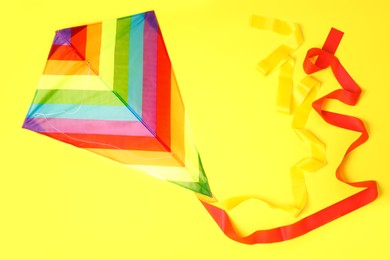 Photo of Bright rainbow kite on yellow background, top view