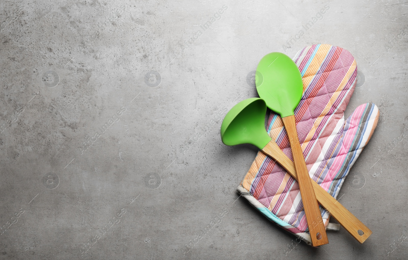 Photo of Different kitchen utensils and oven mitten on grey background, top view with space for text