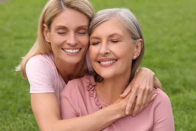 Photo of Happy mature mother and her daughter hugging outdoors