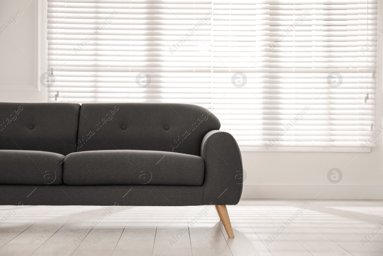 Photo of Comfortable grey sofa near window indoors. Interior design