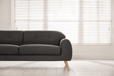 Photo of Comfortable grey sofa near window indoors. Interior design