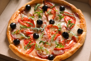 Photo of Tasty fresh pizza with olives in cardboard box, closeup