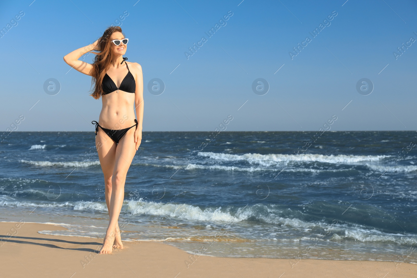 Photo of Beautiful woman in bikini on sea coast. Space for text