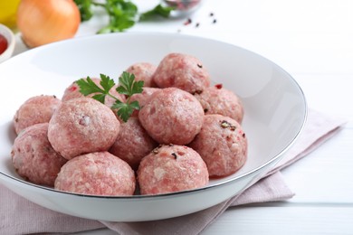 Photo of Many fresh raw meatballs on white wooden table, closeup