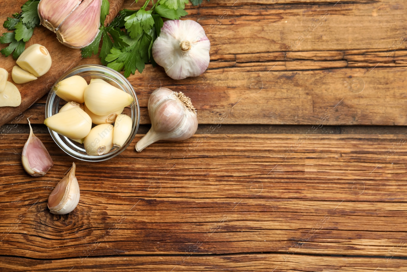 Photo of Flat lay composition with fresh garlic bulbs and cloves on wooden table, space for text. Organic product