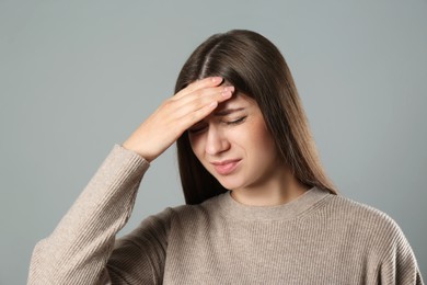 Photo of Young woman suffering from migraine on grey background