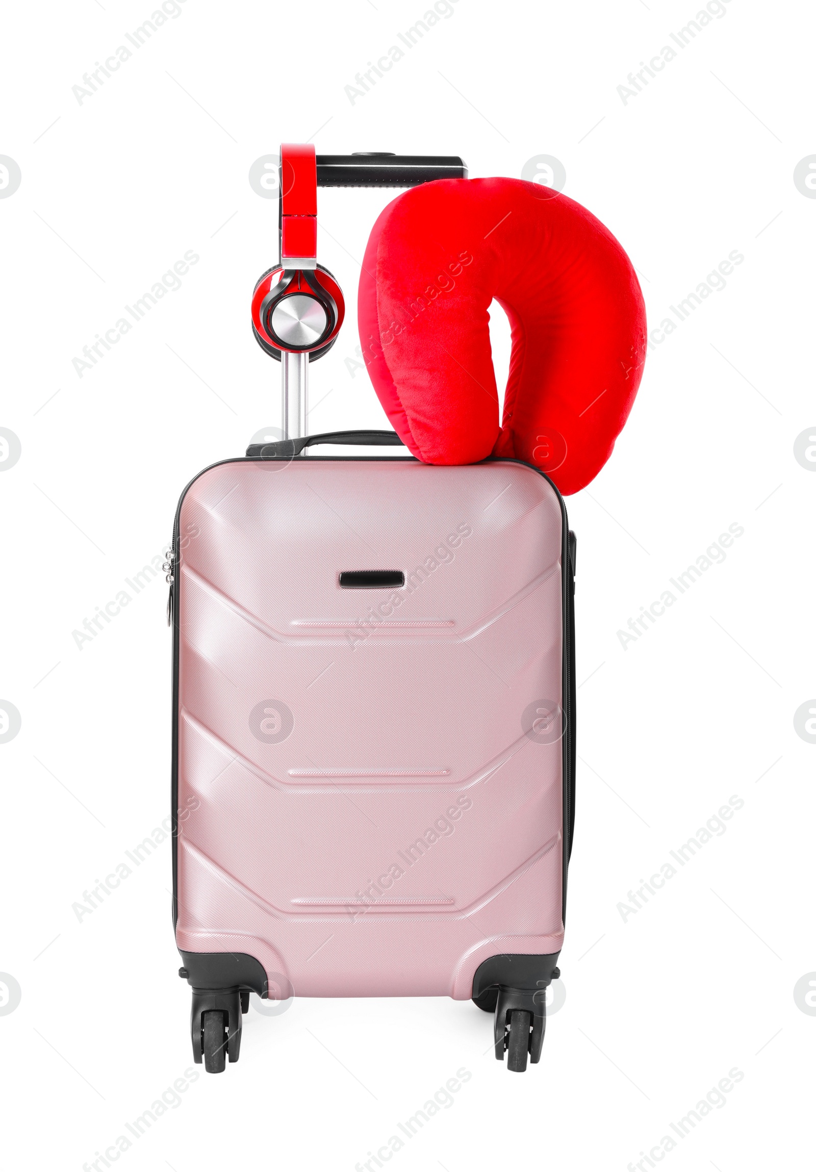 Photo of Red travel pillow and headphones on suitcase against white background