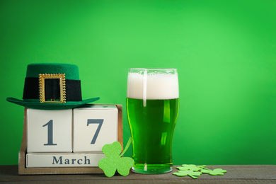 Photo of Composition with green beer and clover leaves on wooden table. St. Patrick's Day celebration