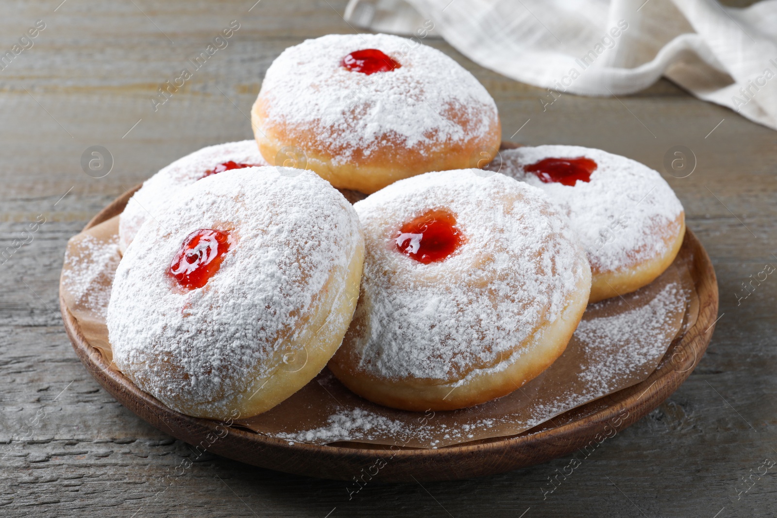 Photo of Delicious donuts with jelly and powdered sugar on wooden table