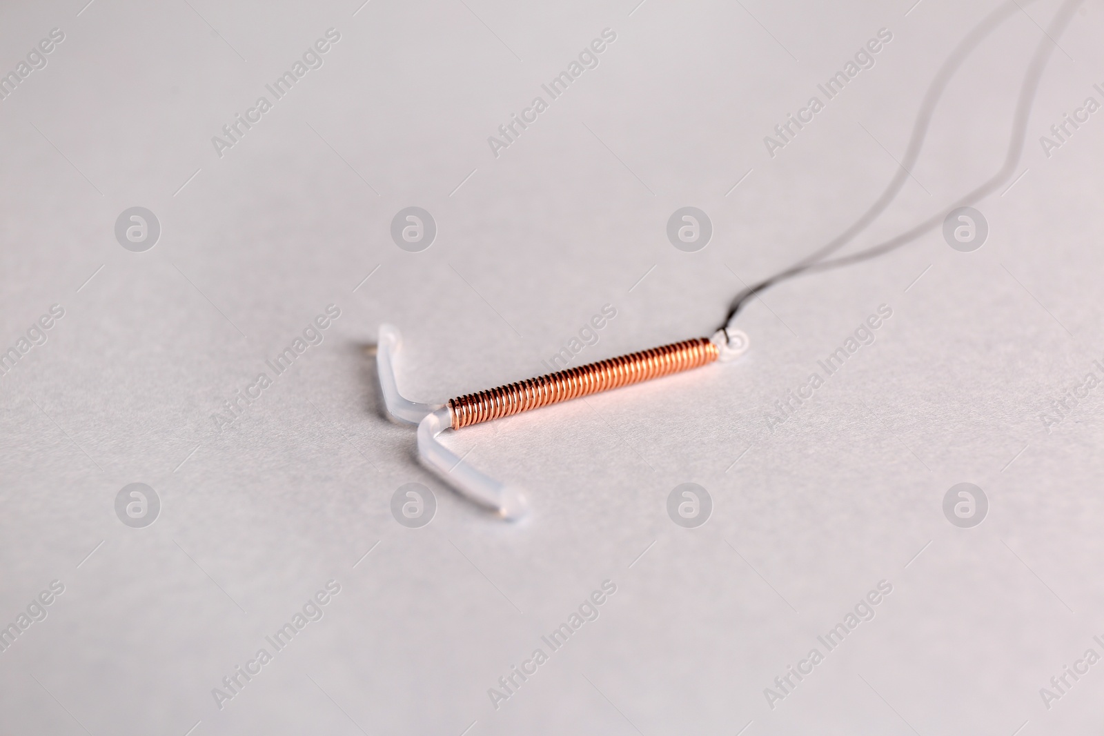 Photo of T-shaped intrauterine birth control device on light background