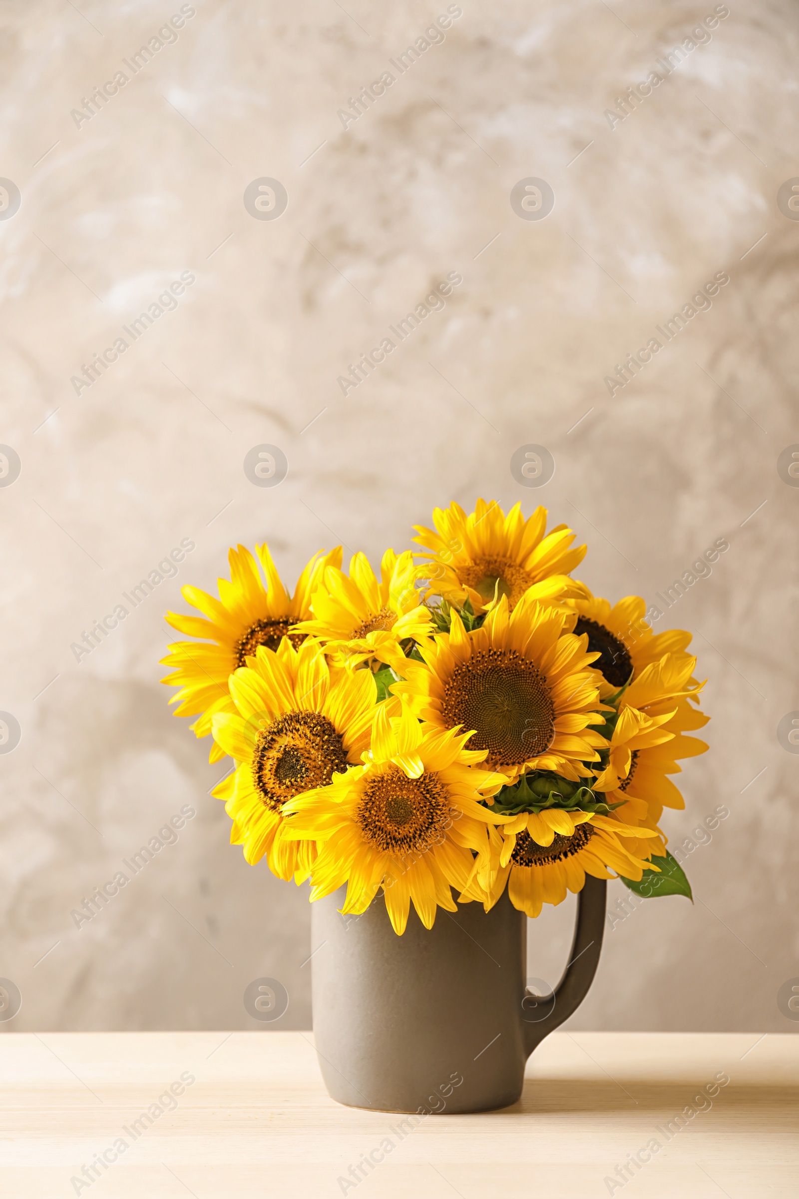 Photo of Jug with beautiful yellow sunflowers on table